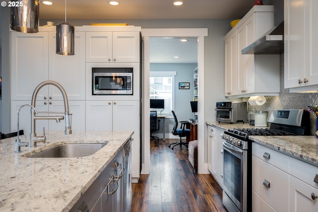 kitchen with stainless steel appliances, white cabinetry, sink, and light stone counters