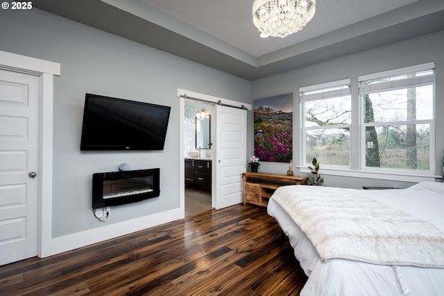 bedroom with ensuite bathroom, a barn door, dark hardwood / wood-style floors, and an inviting chandelier