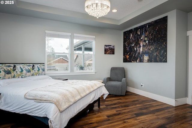 bedroom featuring a tray ceiling, dark hardwood / wood-style floors, and a chandelier