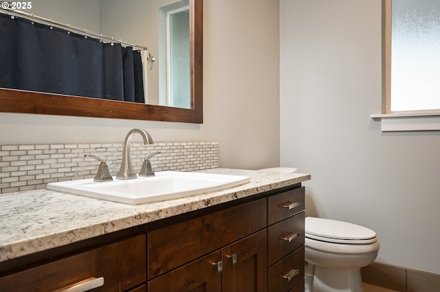 bathroom with vanity, toilet, and decorative backsplash