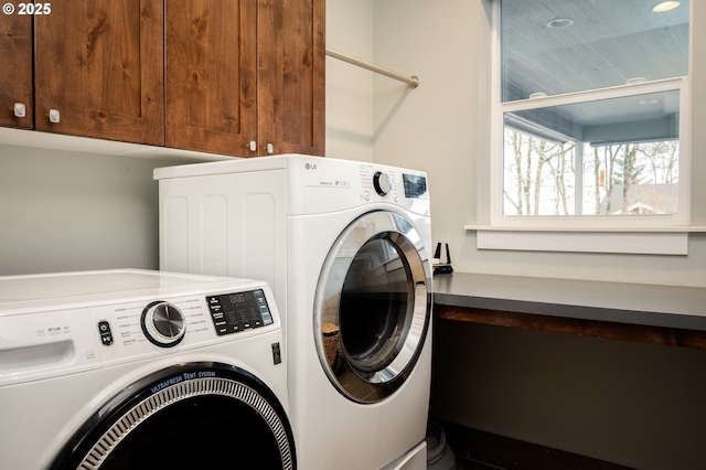 clothes washing area featuring washer and dryer and cabinets