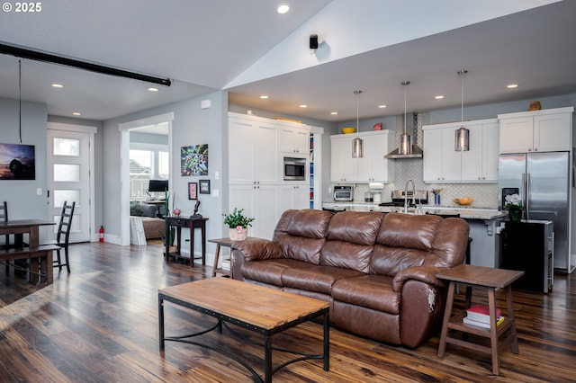 living room featuring dark wood-type flooring, sink, and vaulted ceiling