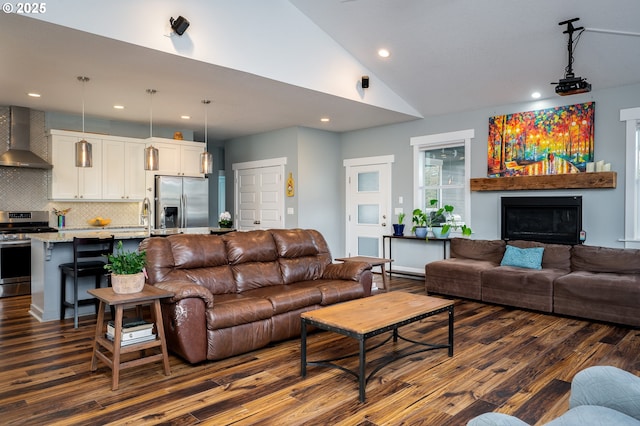 living room featuring high vaulted ceiling, sink, and dark hardwood / wood-style flooring