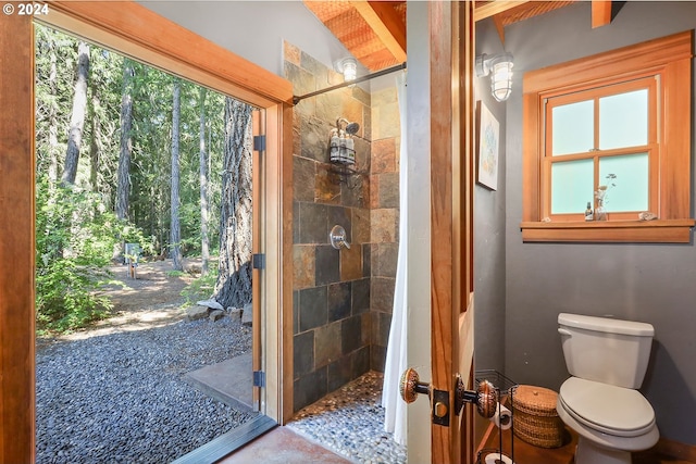 bathroom featuring tiled shower and toilet