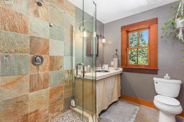 bathroom featuring a stall shower, vanity, toilet, and baseboards