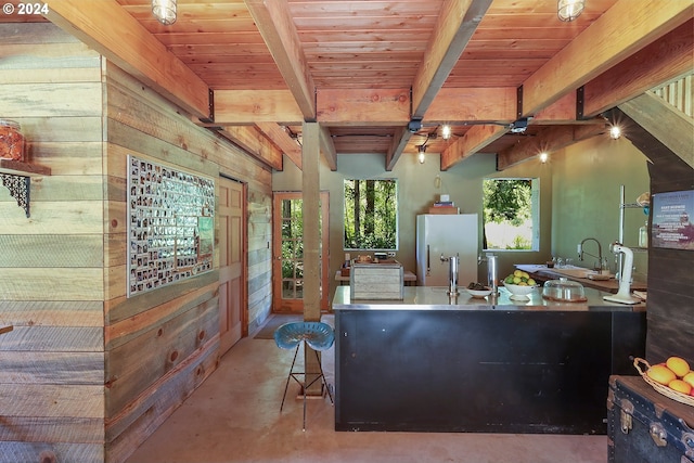 kitchen featuring wood ceiling, beamed ceiling, a sink, and freestanding refrigerator