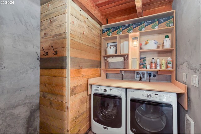 clothes washing area featuring wooden ceiling and washer and clothes dryer