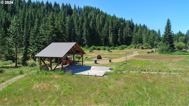 view of community featuring a forest view, a yard, and a gazebo