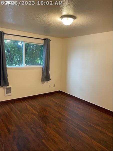 5136 SE 17th Ave, Portland, OR 97202 - spare room featuring baseboards, dark wood-style flooring, and a textured ceiling