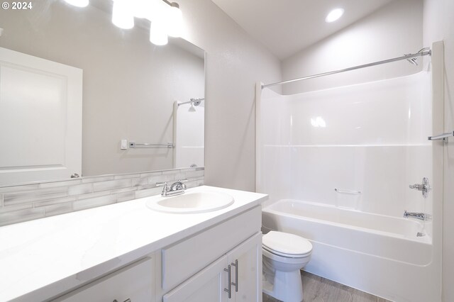 full bathroom with decorative backsplash, vanity, wood-type flooring, washtub / shower combination, and toilet