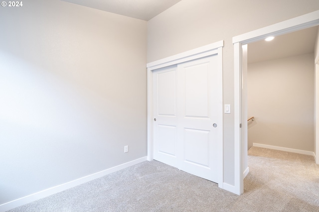 unfurnished bedroom with a closet and light colored carpet