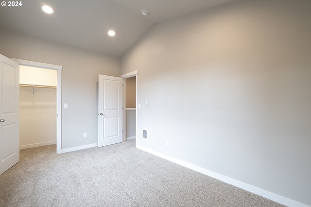 unfurnished bedroom with a closet, light colored carpet, and lofted ceiling