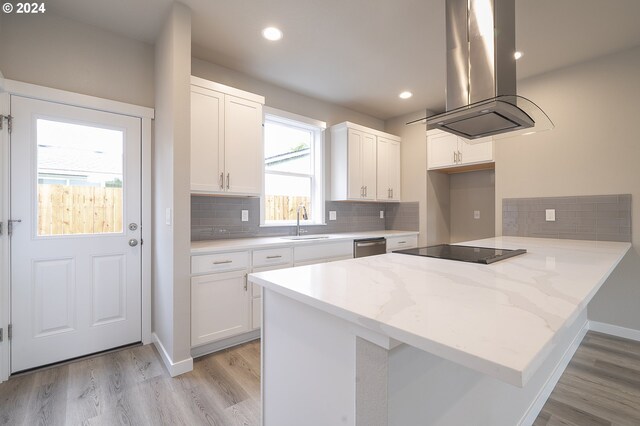 kitchen with black electric stovetop, island range hood, sink, light hardwood / wood-style flooring, and white cabinets