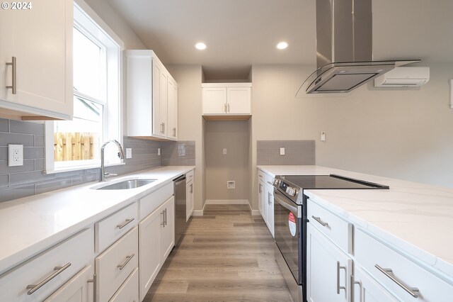 kitchen with appliances with stainless steel finishes, sink, light hardwood / wood-style flooring, white cabinetry, and range hood