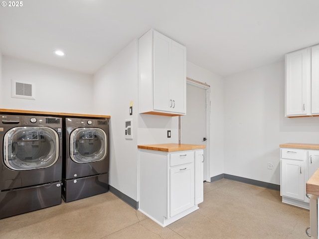 clothes washing area featuring cabinets and washer and dryer