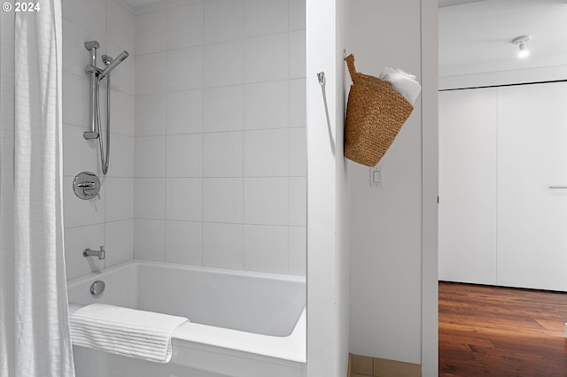 bathroom with shower / bathtub combination with curtain and wood-type flooring