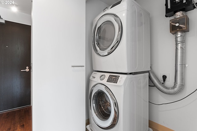 clothes washing area featuring dark wood-type flooring and stacked washer and clothes dryer