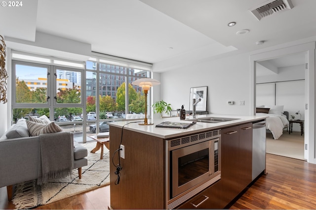 kitchen featuring appliances with stainless steel finishes, a kitchen island with sink, sink, and dark wood-type flooring