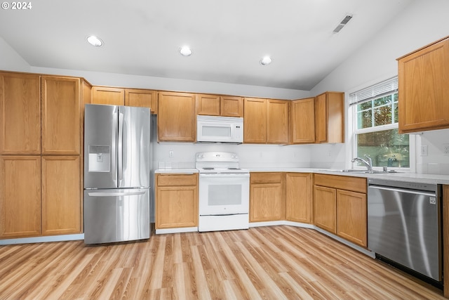 kitchen with appliances with stainless steel finishes, light wood-type flooring, lofted ceiling, and sink