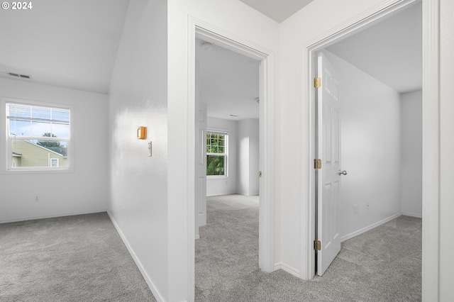 hallway with light colored carpet, lofted ceiling, and a wealth of natural light