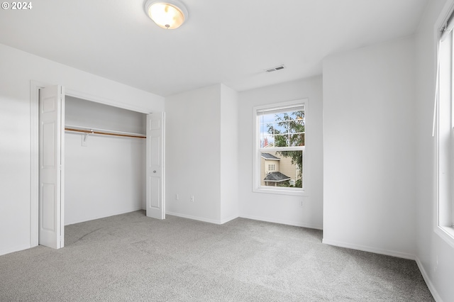 unfurnished bedroom featuring light colored carpet and a closet