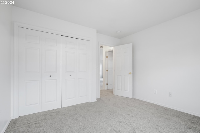 unfurnished bedroom featuring light carpet and a closet