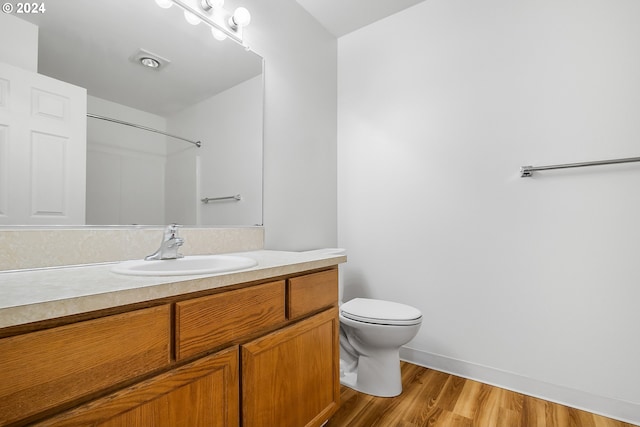 bathroom featuring a shower, toilet, vanity, and hardwood / wood-style flooring