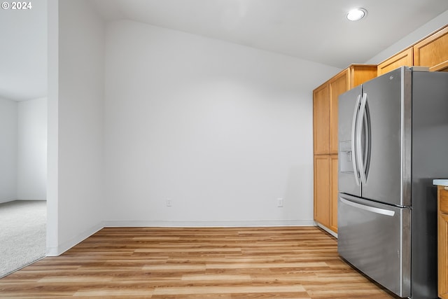 kitchen with stainless steel refrigerator with ice dispenser, light hardwood / wood-style floors, and lofted ceiling