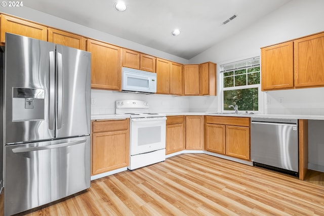 kitchen with light wood-type flooring, sink, appliances with stainless steel finishes, and vaulted ceiling