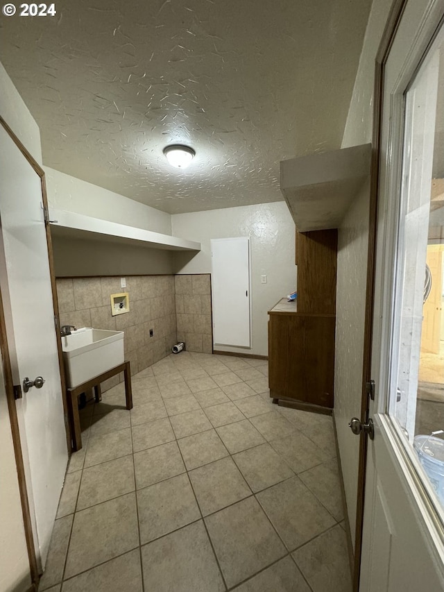 clothes washing area with electric dryer hookup, tile walls, a textured ceiling, light tile patterned floors, and hookup for a washing machine