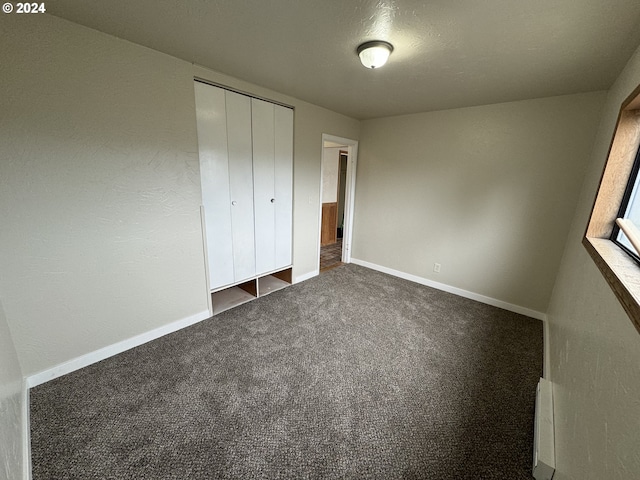 unfurnished bedroom featuring a closet and dark carpet