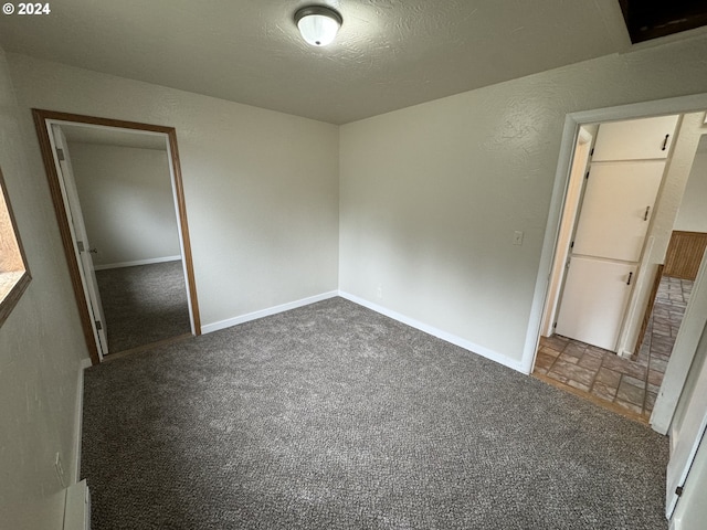 unfurnished bedroom with dark colored carpet, a closet, and a textured ceiling