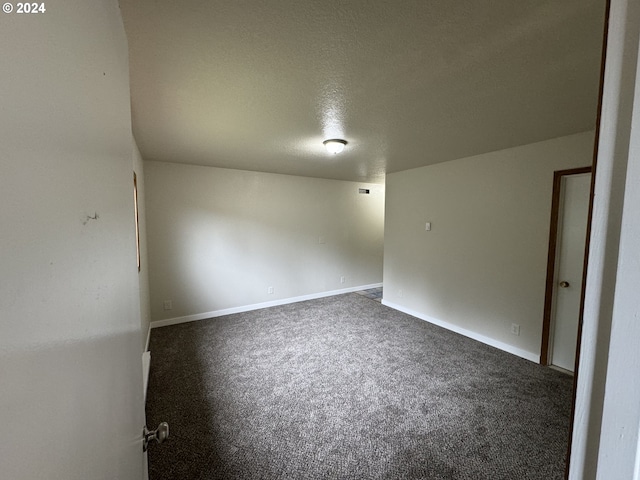 carpeted empty room featuring a textured ceiling