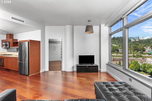 unfurnished living room with visible vents, dark wood-type flooring, and baseboards