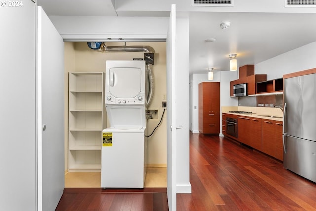 interior space featuring stacked washing maching and dryer, sink, and dark hardwood / wood-style flooring