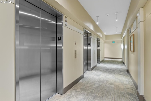 corridor with elevator, baseboards, a package area, and light carpet