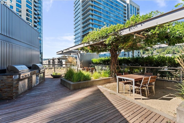 deck featuring outdoor dining space, an outdoor kitchen, fence, and area for grilling