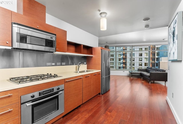 kitchen with a sink, open shelves, dark wood finished floors, appliances with stainless steel finishes, and light countertops