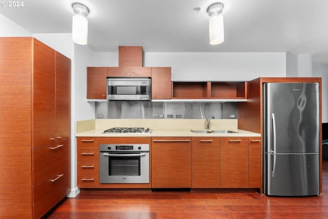 kitchen featuring dark wood finished floors, stainless steel appliances, light countertops, and a sink