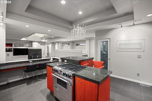 kitchen with rail lighting, high end range, a center island, and a raised ceiling