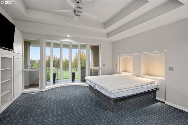 unfurnished bedroom featuring a tray ceiling, dark colored carpet, and ceiling fan