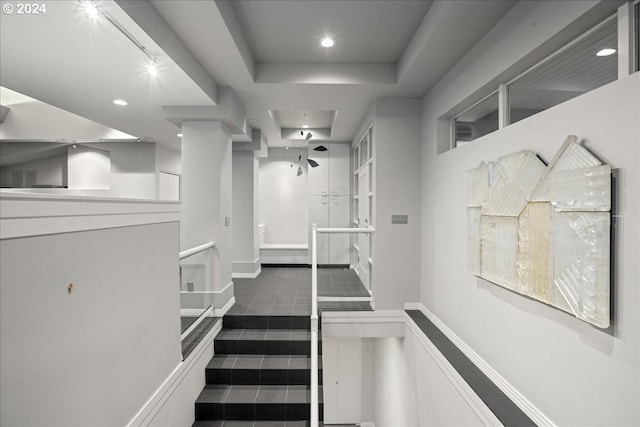 staircase with a raised ceiling and tile patterned floors