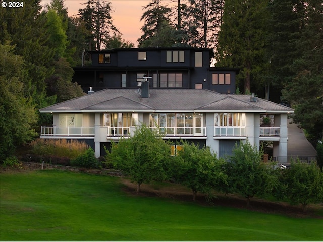 back house at dusk with a lawn