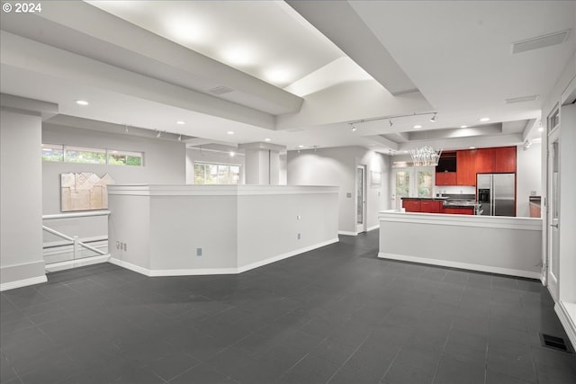 unfurnished living room featuring a tray ceiling and track lighting