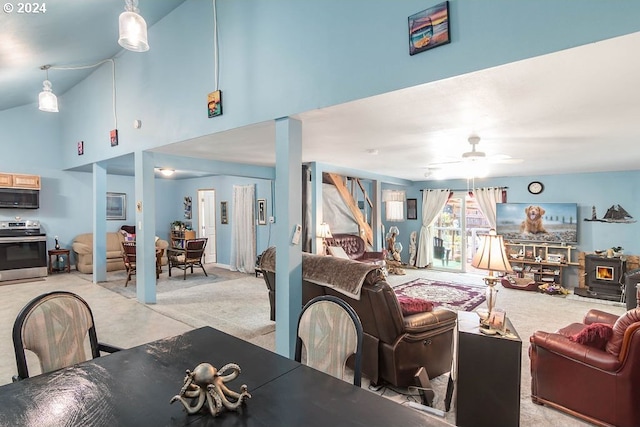 dining room featuring light carpet, a wood stove, high vaulted ceiling, and ceiling fan