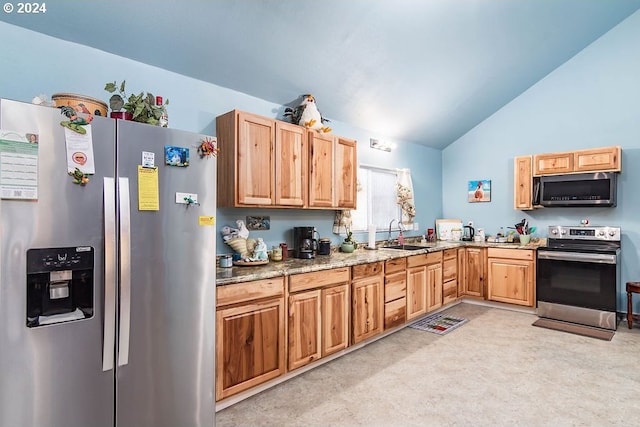 kitchen with light stone countertops, sink, appliances with stainless steel finishes, and lofted ceiling