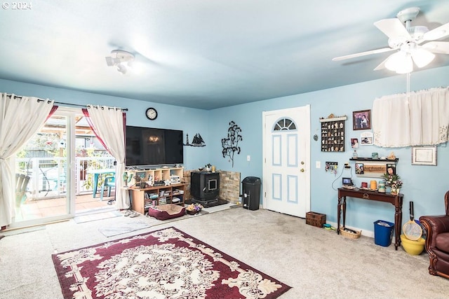 carpeted living room featuring ceiling fan and a wood stove