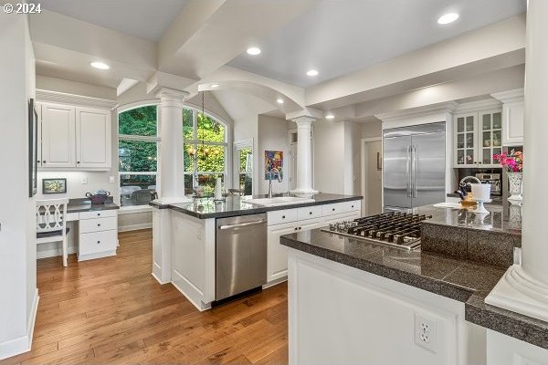 kitchen with hardwood / wood-style floors, sink, stainless steel appliances, and white cabinets