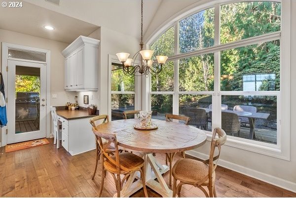 dining space with a chandelier, light hardwood / wood-style flooring, and vaulted ceiling