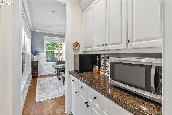 kitchen featuring light wood-type flooring, ornamental molding, and white cabinets